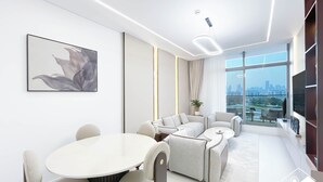 Een moderne woonkamer met een ronde eettafel, banken en een groot raam met uitzicht op de stad.