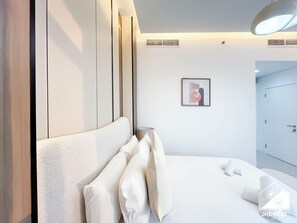 Ein modernes Hotelzimmer mit einem großen Bett, einem Nachttisch, einer Lampe und einem gerahmten Bild an der Wand.