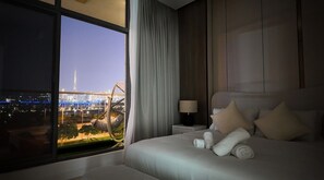 A hotel room with a large bed, a nightstand, a lamp, and a view of a cityscape including a bridge and a tower. - Luxury 1BR w/ Balcony & Burj Khalifa View (Dubai)