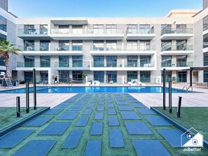Ein modernes Gebäude mit Schwimmbad, Sitzgelegenheiten im Freien und blauem Himmel.