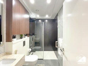 Ein modernes Badezimmer mit Duschkabine aus Glas, Toilette und Waschbecken.