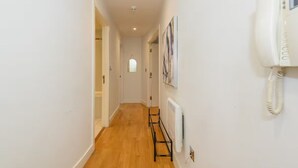 A narrow hallway with wooden flooring, white walls, and a telephone mounted on the wall. - Prime apartment in Leeds - Central location (Leeds)