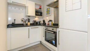 A modern kitchen with white cabinets, a black countertop, and an oven. - Prime apartment in Leeds - Central location (Leeds)