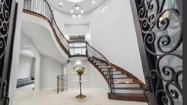 A grand staircase with a wooden handrail and black wrought iron balustrades, leading to an upper floor. - Gorgeous 7200 sq ft  estate with AC in vibrant Houston Galleria Area (Houston)