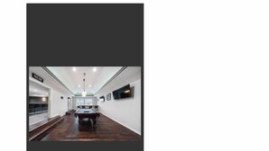 A spacious hallway with a pool table, a TV mounted on the wall, and a sign indicating a spa area. - Gorgeous 7200 sq ft  estate with AC in vibrant Houston Galleria Area (Houston)
