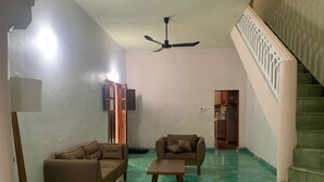 Un soggiorno con due divani, un tavolino, una ventola a soffitto e una scala.