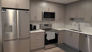 A modern kitchen with stainless steel appliances, wooden cabinets, and a marble countertop.