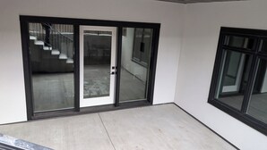 A modern building with large glass doors leading to a covered outdoor area with a staircase.