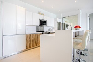 A modern kitchen with white cabinets, a microwave, and a wooden accent wall.
