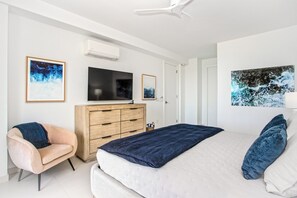 A bedroom with a bed, a dresser, a TV, and artwork on the walls.