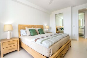 Ein Schlafzimmer mit einem hölzernen Bett, zwei Nachttischen, einem Spiegel und Blick ins Badezimmer.