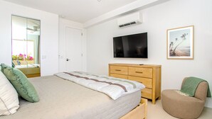 Ein Schlafzimmer mit Bett, Fernseher, Kommode und Stuhl.