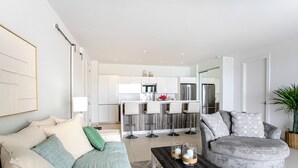 Ein modernes Wohnzimmer mit einer Couch, einem Couchtisch und einem Essbereich mit Barhocker.