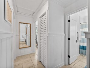 A hallway with white walls, a wooden-framed mirror, a door with a striped curtain, and a tiled floor. - Seahorse Cottage 2 - 2/2 with Private Beach (Englewood)