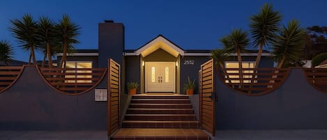 A modern house with a front entrance, a number '2552' on the wall, and a staircase leading up to the door.