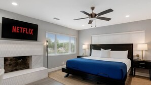A modern hotel room with a bed, a fireplace, a ceiling fan, and a TV screen displaying 'NETFLIX'. - Bella| Pool/Spa|Downtown|Freeways|Beaches (San Diego)
