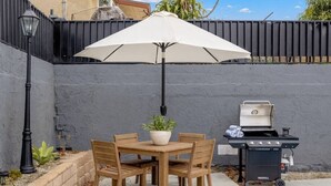 An outdoor patio with a table and chairs, a grill, and a potted plant. - Bella| Pool/Spa|Downtown|Freeways|Beaches (San Diego)
