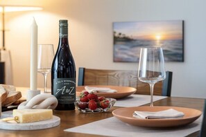 A dining table with a bottle of wine, glasses, a candle, cheese, and strawberries. - Bella| Pool/Spa|Downtown|Freeways|Beaches (San Diego)