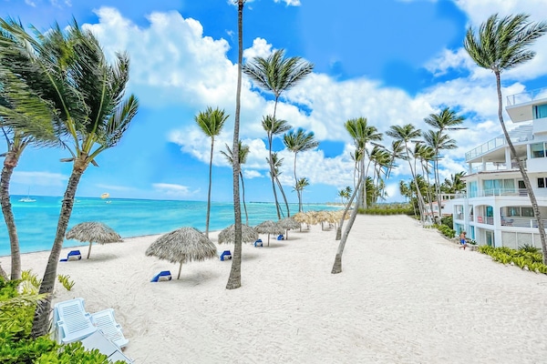 Na praia, areia branca, espreguiçadeiras, guarda-sóis