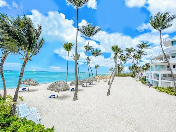 Am Strand, weißer Sandstrand, Liegestühle, Sonnenschirme
