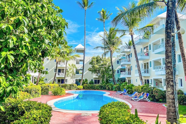 Una piscina al aire libre, sombrillas, sillones reclinables de piscina