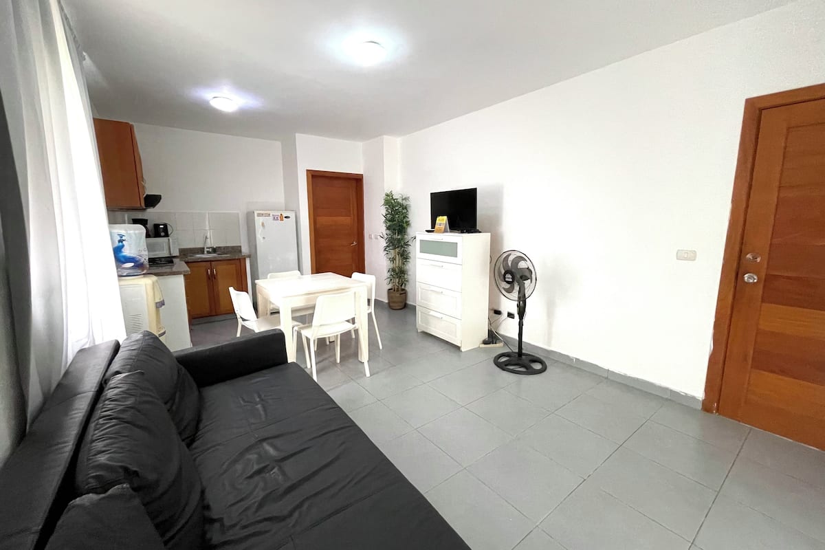 A modern apartment with a living room, dining area, kitchen, and a small balcony.