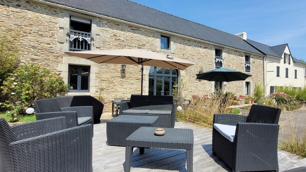 A stone building with outdoor seating and umbrellas. - La Maison Keribin 4****, Luxury traditional self catering cottage with its private Jacuzzi (Min stay 3 nights) (MOELAN SUR MER)