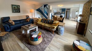 A spacious living room with a blue sofa, a yellow sofa, and a coffee table. There is a staircase in the background leading to the kitchen. - La Maison Keribin 4****, Luxury traditional self catering cottage with its private Jacuzzi (Min stay 3 nights) (MOELAN SUR MER)