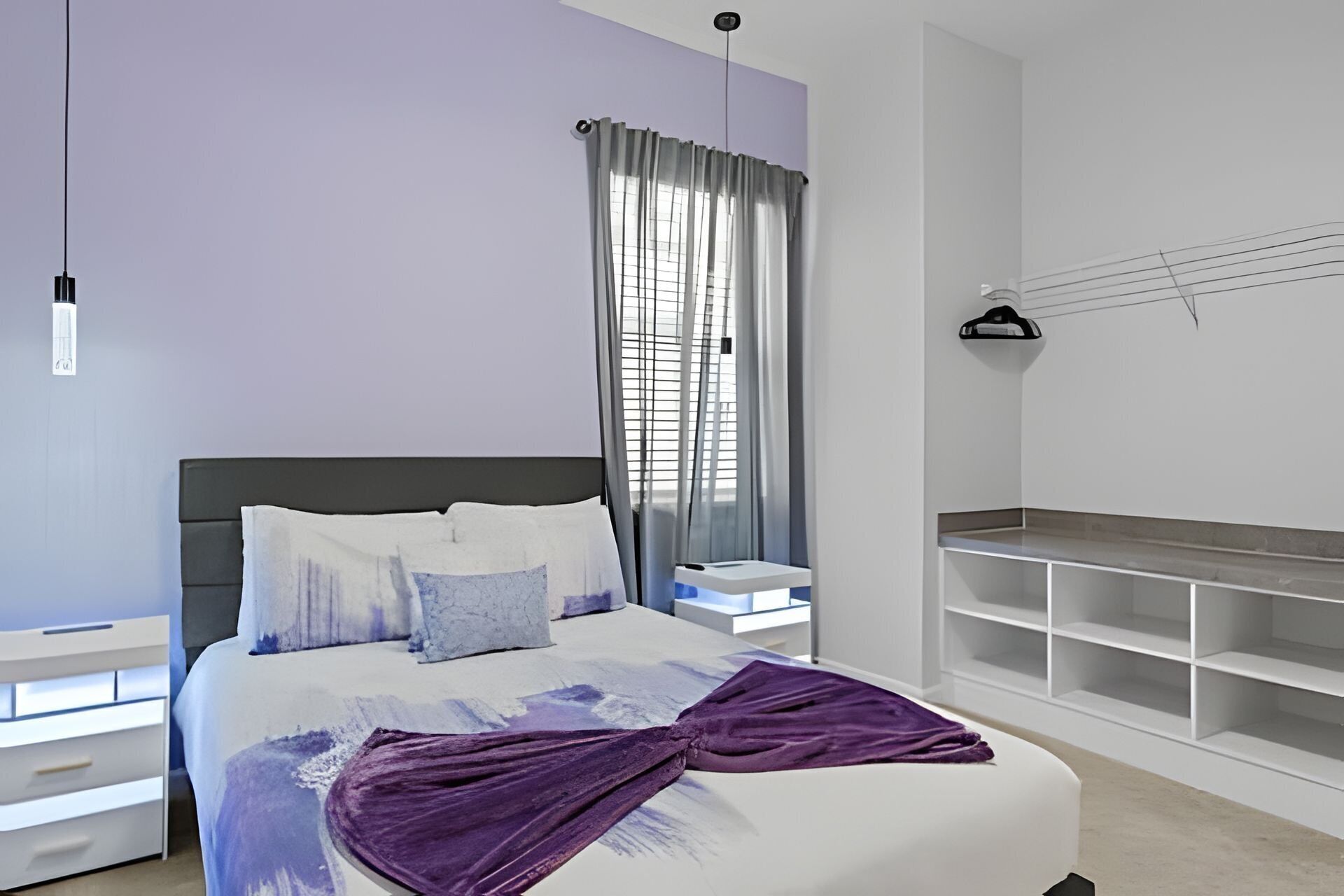 Een moderne slaapkamer met een bed, nachtkastje, venster met gordijnen en ingebouwde kasten.