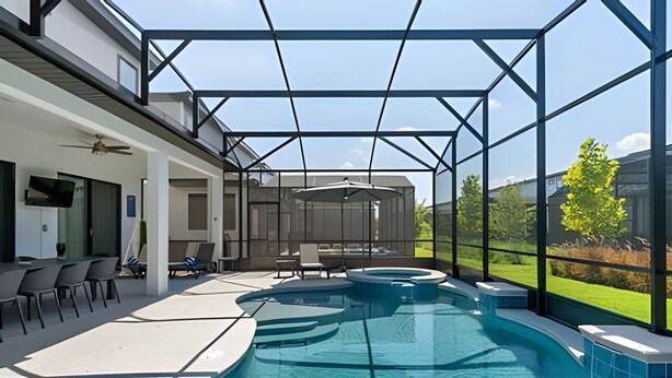 A modern outdoor pool area with a glass enclosure, a seating area with chairs and a table, and a view of the surrounding greenery. - Luxurious 9BR Paradiso Pool, Cinema & Game Room (Orlando)