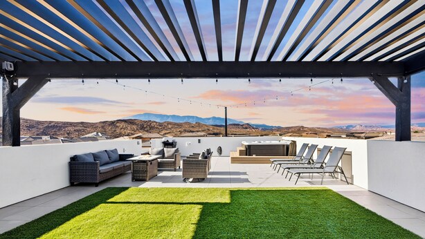 En tagterrasse med pergola, udendørs møbler og udsigt til bjerge.