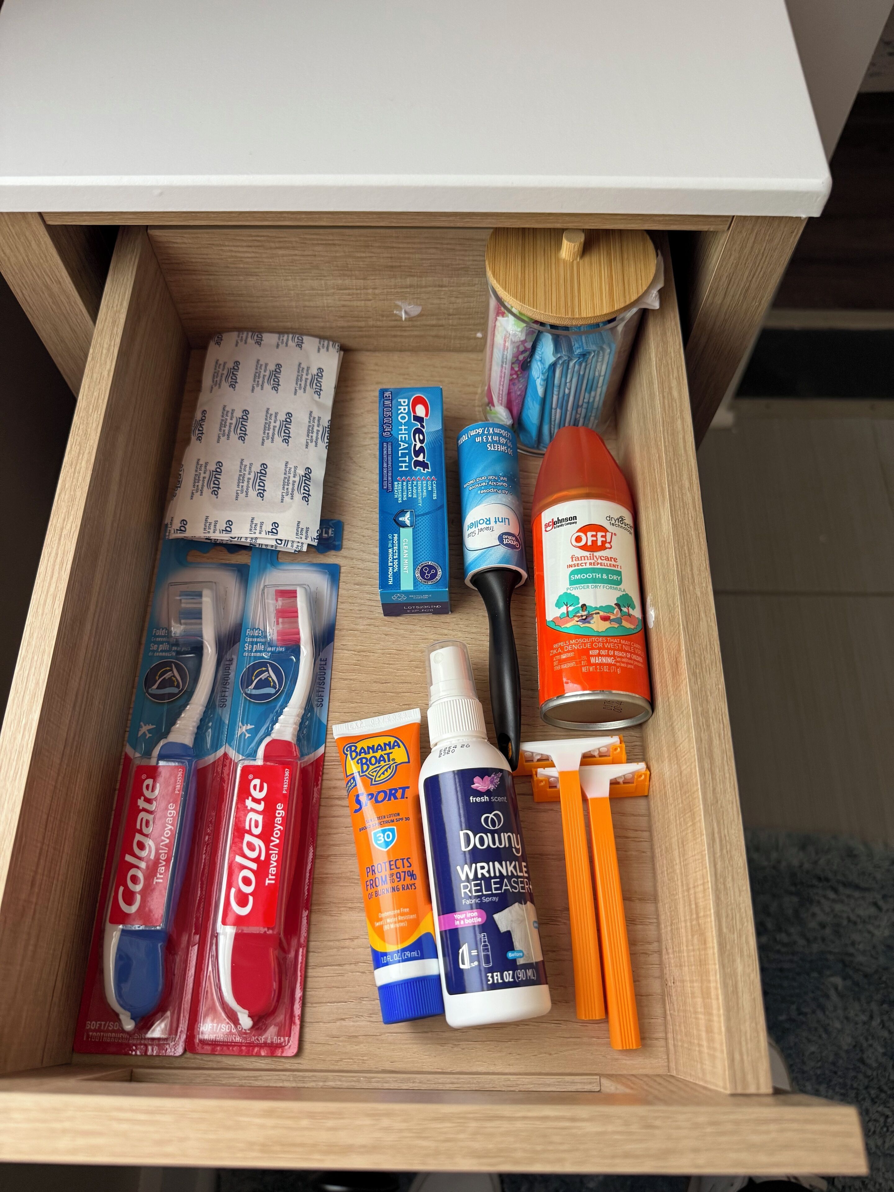 Un tiroir contenant divers articles de toilette, notamment des brosses à dents, du dentifrice et une brosse à cheveux.