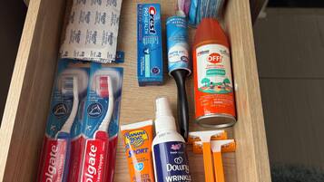 Un tiroir contenant divers articles de toilette, notamment des brosses à dents, du dentifrice et une brosse à cheveux.