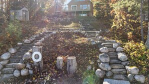 A stone staircase leading to a house surrounded by autumn foliage. - 4BR Lakefront Home | Kayaks, Fire Pit & Views (Hawks)