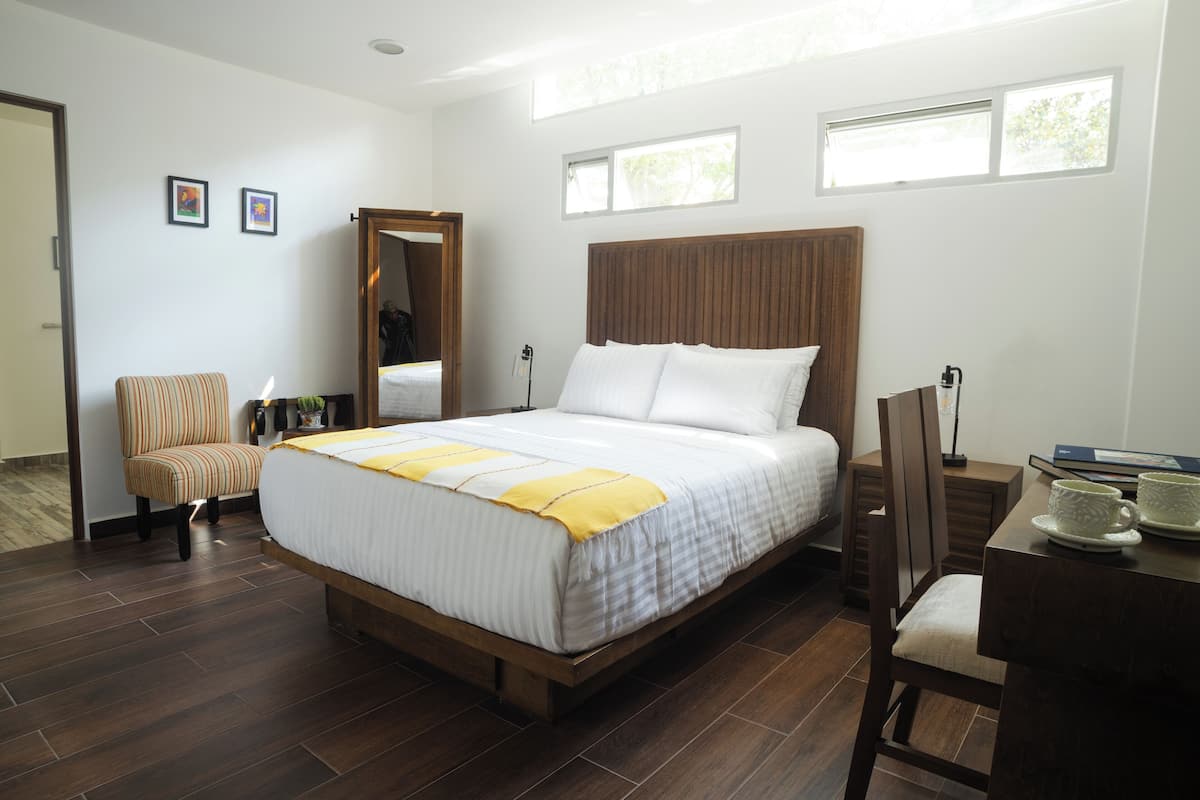 Una habitación de hotel con una cama grande, una silla, una mesita y una ventana.