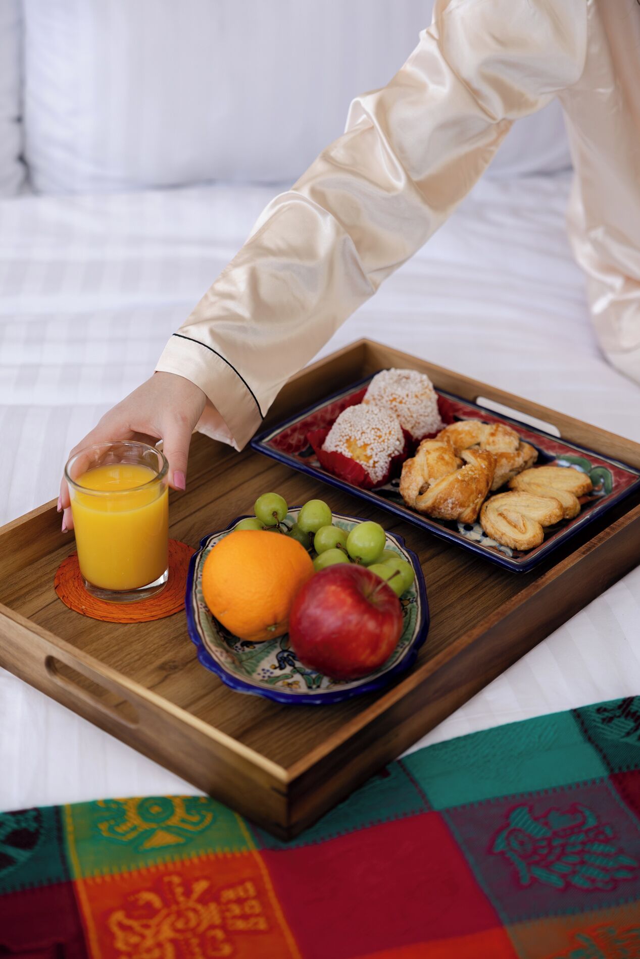 Ein Tablett mit Orangensaftgläser, Obstschale und Gebäck auf einer Unterlage.