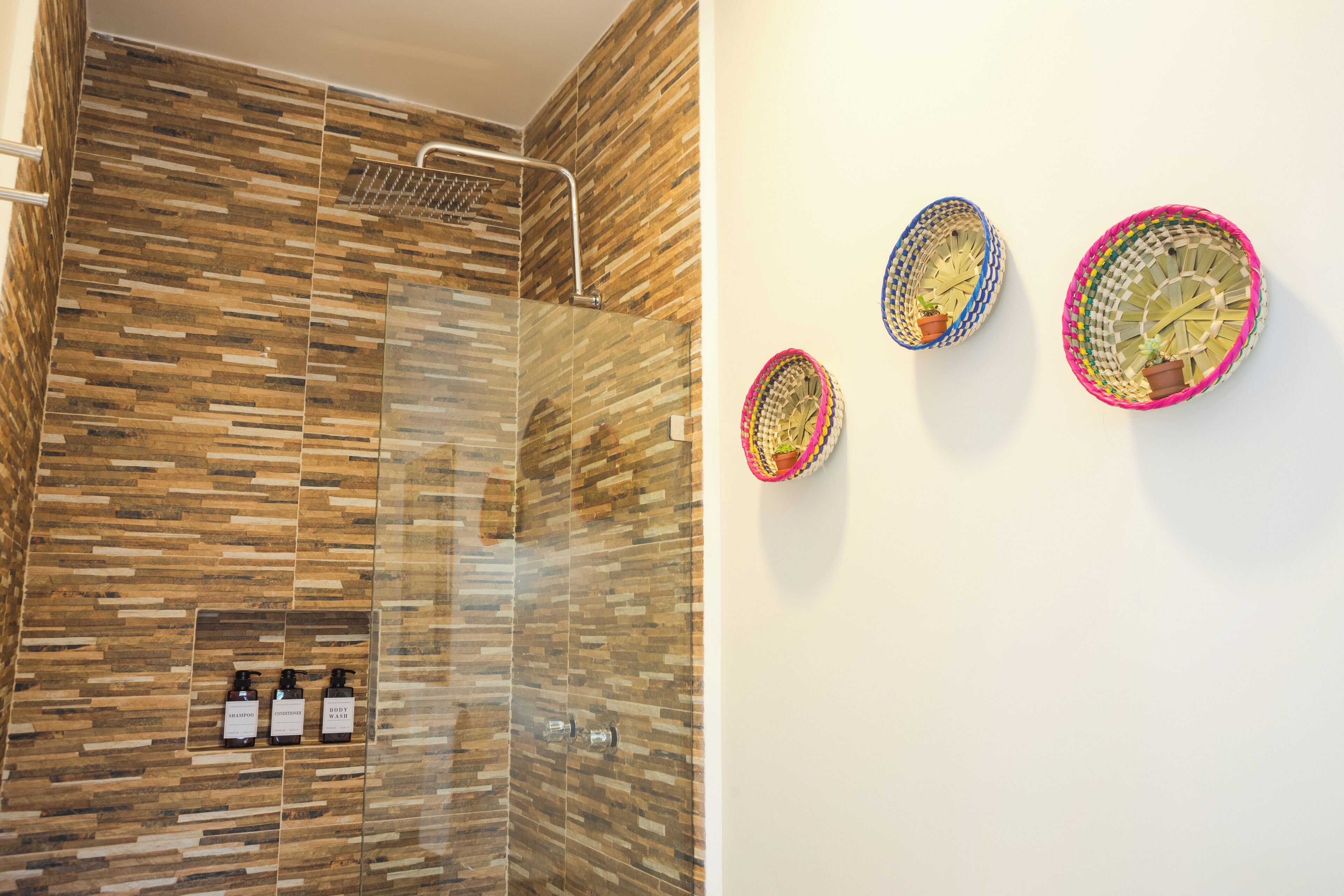 A modern bathroom with a shower area, a glass-enclosed vanity, and three bottles of toiletries.