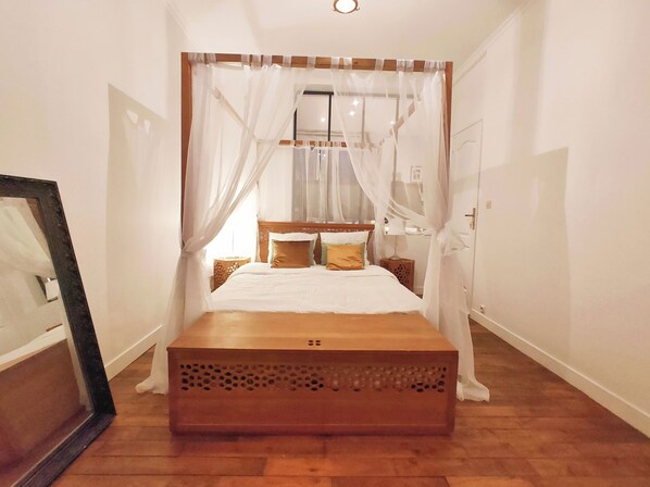 Ein Schlafzimmer mit Baldachinbett, Holz-Kopfteil und Nachttisch.