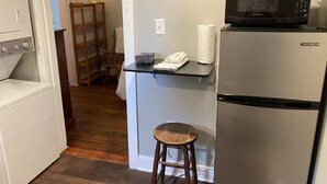 A compact kitchen with a refrigerator, microwave, and a small bar stool. - Cozy Apartment in the heart of town. Monthly min. (Bowling Green)