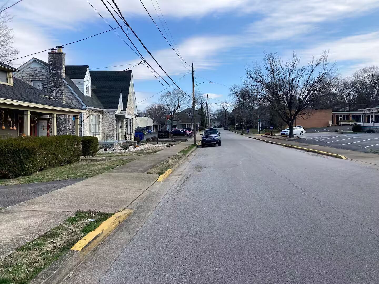 Une rue résidentielle bordée de maisons des deux côtés, un ciel dégagé et une voiture garée au loin.