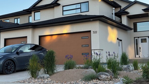 A modern two-story house with a garage, numbered 322, and a driveway with a parked car. - The Soft Fern Retreat | Cozy 2BR suite in Rosewood (Saskatoon)