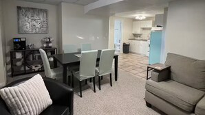 En moderne stue med en sort lædersofa, en grå sofa og et spiseområde med bord og stole.