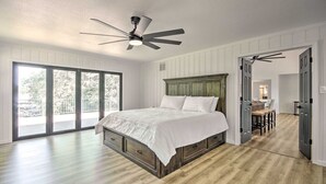 Un dormitorio con una cama grande, ventilador de techo y vista a través de puertas corredizas de vidrio.