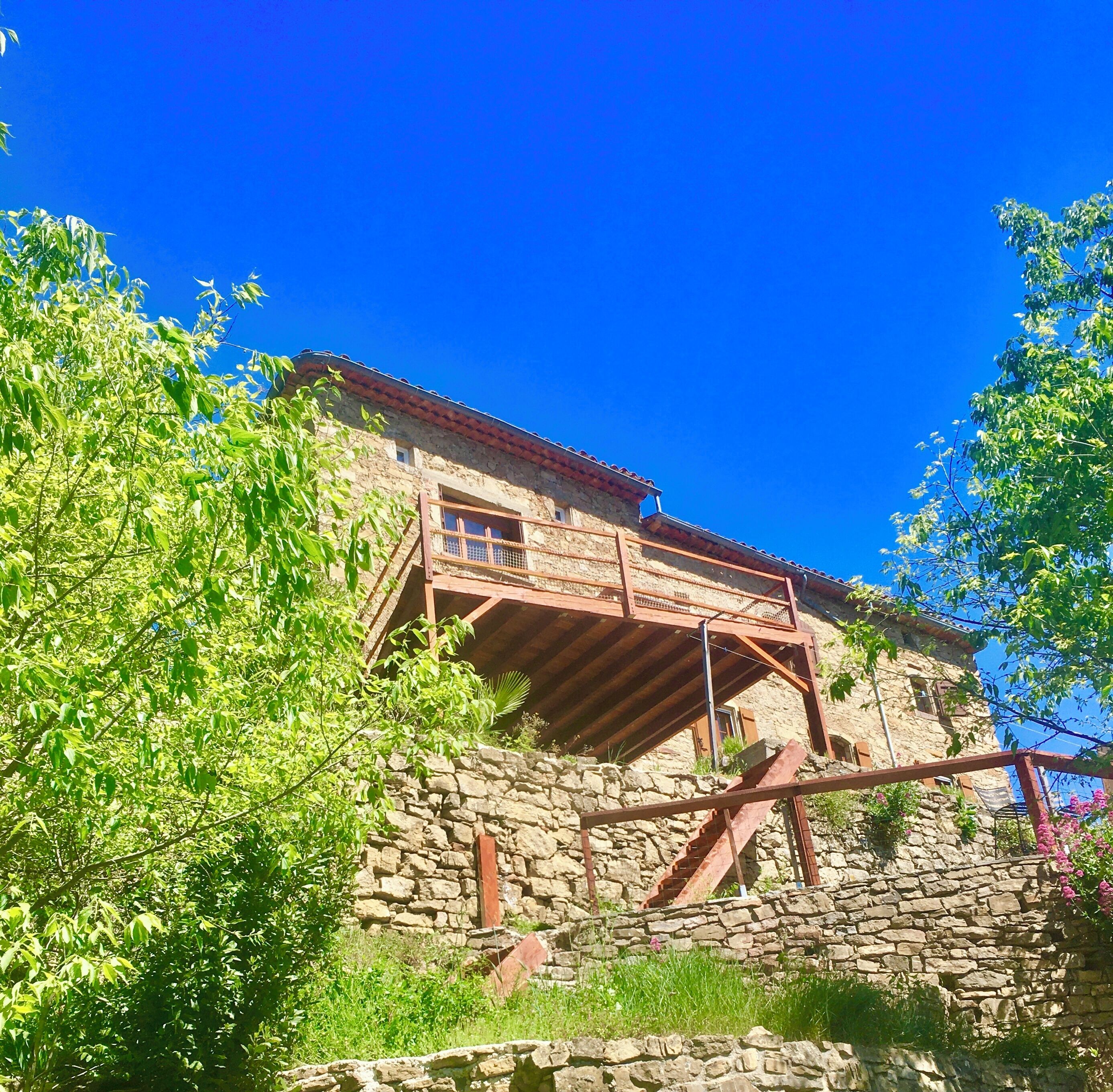 A stone building with a wooden staircase leading to a balcony.