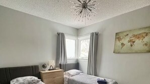 A bedroom with a large bed, two smaller beds, a nightstand, a globe, and a world map on the wall.