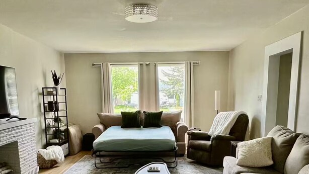 A spacious living room with a large bed, two sofas, a coffee table, and a fireplace.