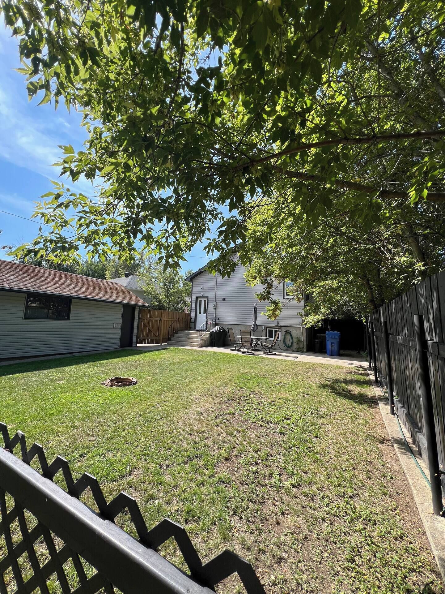 Un jardin avec une pelouse, une clôture en bois et une maison avec un garage.