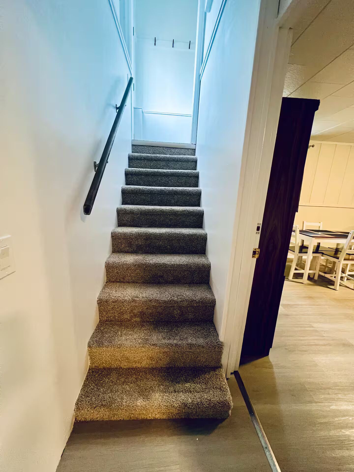 Una escalera alfombrada con barandilla que lleva a un rellano con ventana.