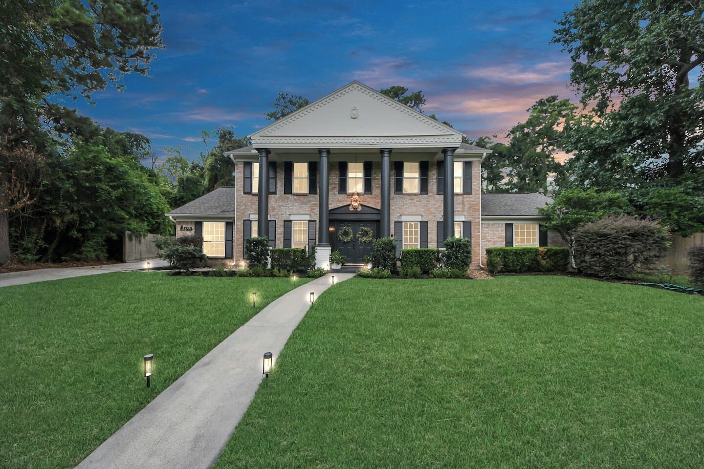 A large, two-story house with a symmetrical facade, a central entrance, and a well-maintained lawn.