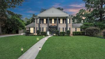 A large, two-story house with a symmetrical facade, a central entrance, and a well-maintained lawn.